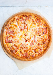 Pizza with mozzarella cheese, ham, tomatoes and sauce on plain grey background