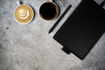 Minimal workspace graphic tablet with coffee cup. copy space on a gray stone table background. Top...