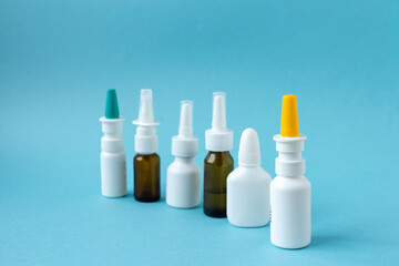 Bottles of nasal spray standing in line on blue background, medicine flat lay, treatment for colds,...