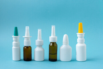 Bottles of nasal spray standing in line on blue background, medicine flat lay, treatment for colds, medical banner