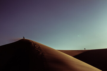Wide shot of people standing on top of sandy dunes at sunset in great sand dunes national park in america