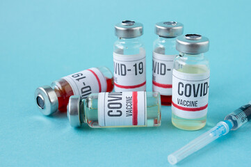 Covid-19 or coronavirus vaccination on blue background, ampoules of vaccine syringe on table, medical banner with copy space