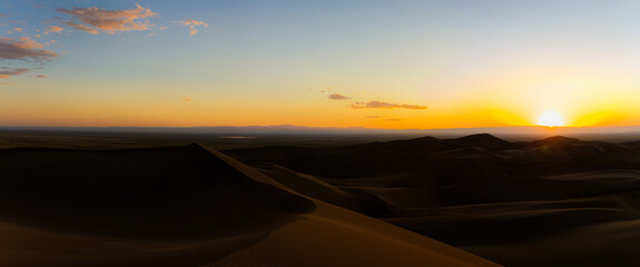 Panorama shot of sandy dunes with orange sunset on horizon in great sand dunes national park in america