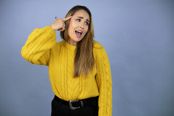 Young beautiful blonde woman with long hair wearing a yellow sweater smiling and thinking with her...
