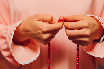 Concentrated woman praying wearing rosary beads. Namaste. Close up hands.