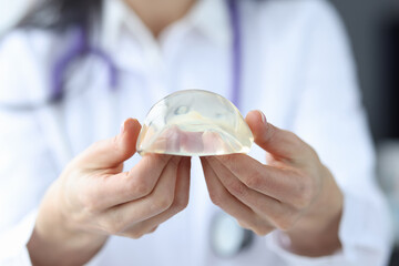 Plastic surgeon holding breast silicone implant closeup
