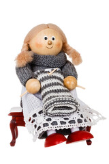 a toy woman sits and knits with knitting needles on a white background