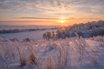 Beautiful winter landscape. Sunrise over the river. Snow-covered trees on the banks of the river.