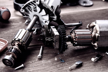 Power tool repair. Details of electrical appliance and repair tools on a wooden table in a repair...