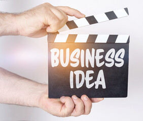 On a white background, a man holds a clapperboard in his hands on which it is written - BUSINESS...