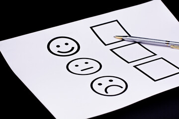 The concept of a customer satisfaction survey and a questionnaire. Provide feedback via a multi-choice form. paper and emoticon emoticon face icons.