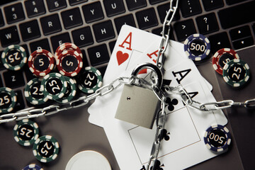 Law and rules for online gambling concept, padlock and playng cards on laptop keyboard.