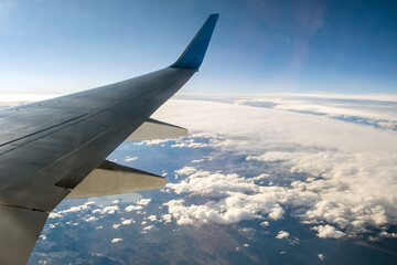 Obraz premium View from airplane on the aircraft white wing flying over cloudy landscape in sunny morning. Air travel and transportation concept.