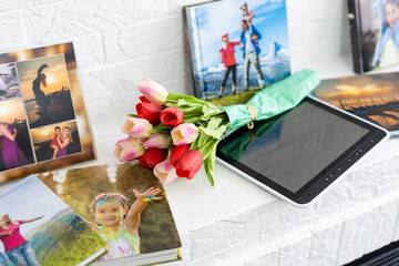 photo book and flowers tulips as a holiday gift lie on the shelf