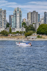 Obraz premium A small boat in a body of water with a city in the background