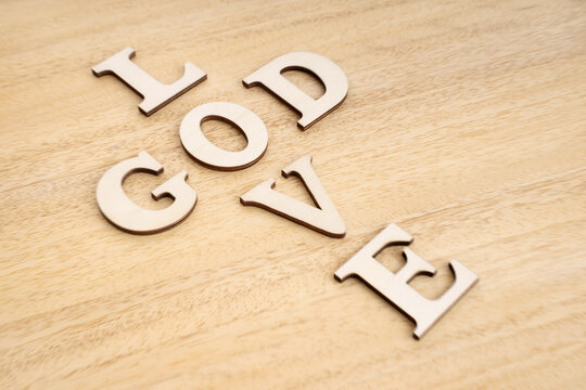 God is Love concept. Words forming a cross on wooden table