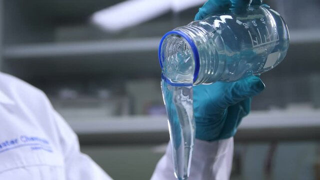 Lab assistant pours transparent jelly from jar in laboratory