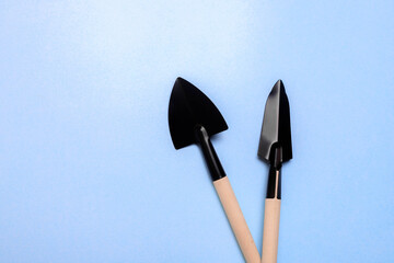 Garden shovels on a blue background . Gardening layout. Spring planting. The care of plants. Work in the ground. Copy space.