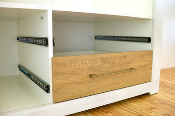 Close up of installation of wooden drawer in contemporary cupboard cabinet.
