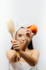 woman shows Dry Brushing body treatment for anti cellulite. Woman using a natural fiber brush with a long handle for cellulite treatment. Skin body care.