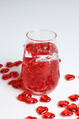 Valentine's Day. Small red glass hearts in a glass of water. A splash of liquid.