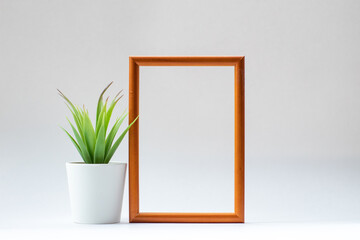 a brown, wooden frame with a green plant and space for text on a white background. Top view.