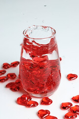 Valentine's Day. Small red glass hearts in a glass of water. A splash of liquid.