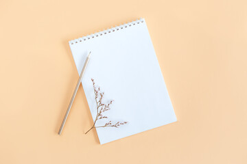 Notebook with blank page and pencil on a yellow background.