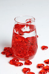 Valentine's Day. Small red glass hearts in a glass of water. A splash of liquid.