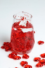 Valentine's Day. Small red glass hearts in a glass of water. A splash of liquid.