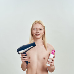 Young blonde man holding hair dryer and fixation liquid