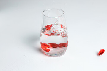 Valentine's Day. Small red glass hearts in a glass of water. A splash of liquid.