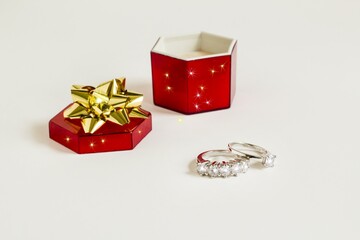 Five stone and single stone diamond,gold rings on white surface with red color ring box.Conceptual image.