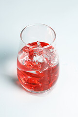 Valentine's Day. Small red glass hearts in a glass of water. A splash of liquid.