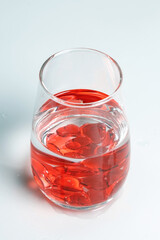 Valentine's Day. Small red glass hearts in a glass of water. A splash of liquid.