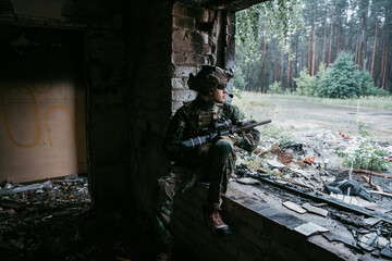 A thoughtful soldier, resting from a military operation while it is raining outside.