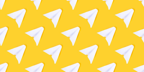 White paper airplane on a yellow background. Concept