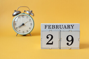 Calendar for February 29 : cubes with the number 29 and the name of the month, alarm clock on a yellow background