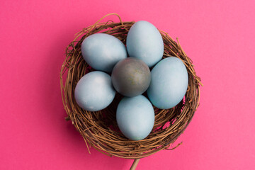 Blue easter hen eggs on dark pink background.
