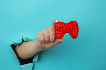 Woman hand showing a thyroid out of a hole torn in blue paper wall. Health care, pharmaceutics and...