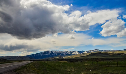 The landscape is in the wild. A road going into the distance, white clouds on the horizon.