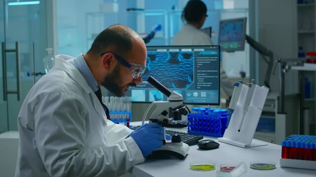 Medical research scientist conducting vaccine development under digital microscope in a biological applied science laboratory. Lab engineer working on medical treatment, typing information on computer