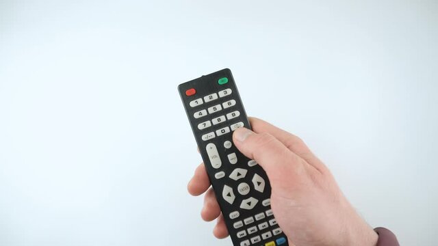 Footage of male hand switching channels with tv remote control.