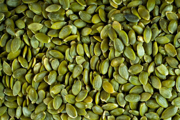 Peeled pumpkin seeds close up. Texture of green seeds.