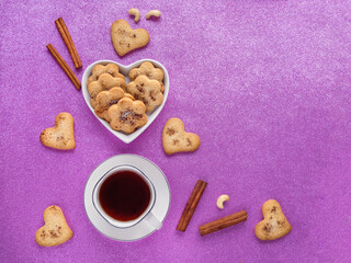 Festive ginger cookies with cinnamon in the shape of hearts are laid out on a pink background. Top view.