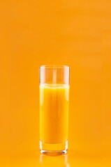 Orange juice in a glass, Natural 100%  on an orange background. Citrus drink. Copy space.