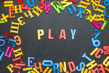 Play, word made from bright color letters on black background