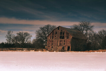 Rural winter scenes of large open fields and sky with barns, farmland and the setting sun.  Ice and...