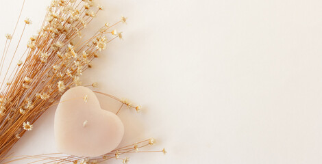 Wide pastel banner with copy space, elegance composition with dried flowers and pink heart candle