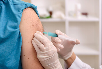Hand of medical staff injecting coronavirus covid-19 vaccine in vaccine syringe to arm muscle